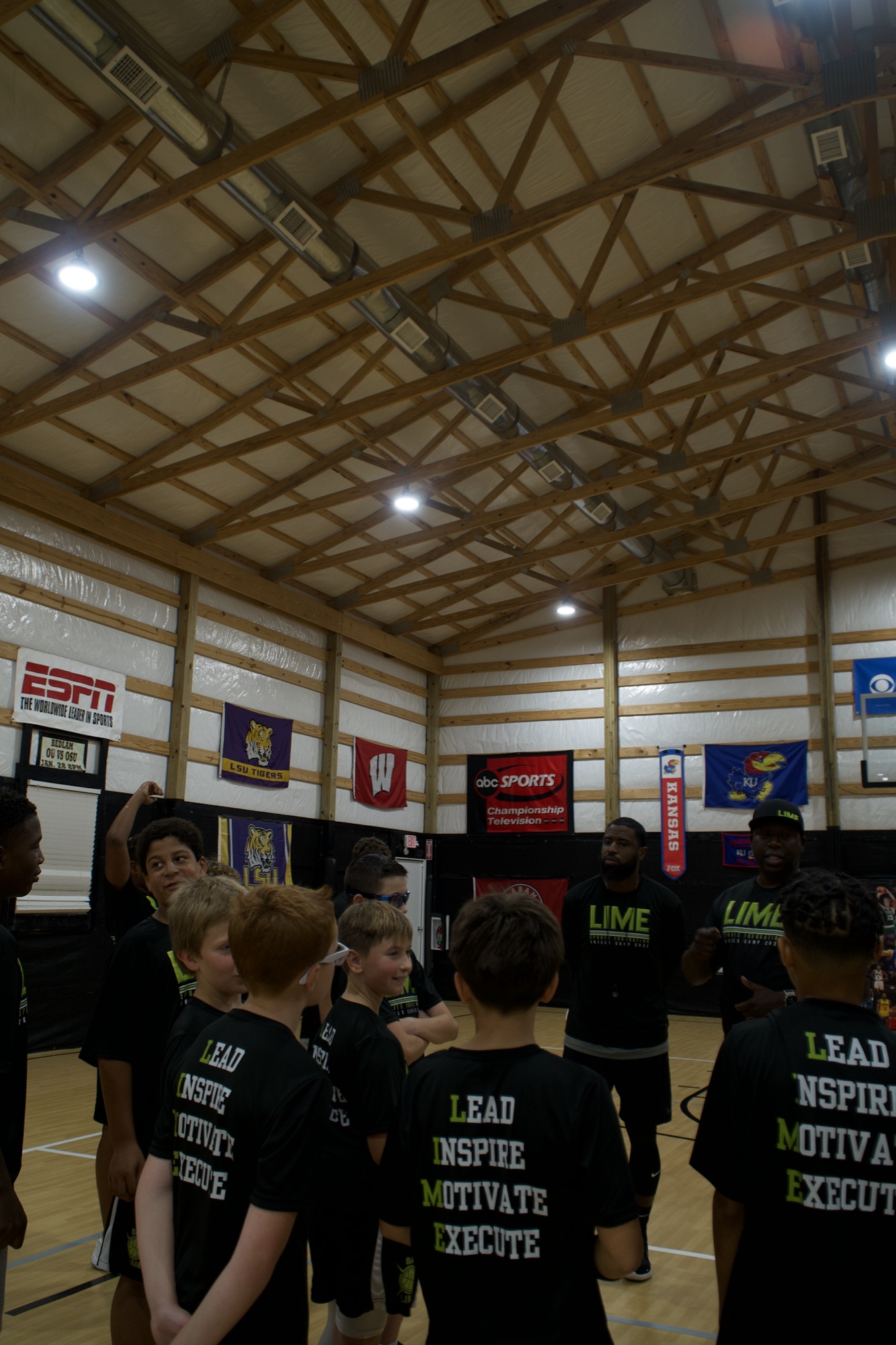 LIME coaches speaking with young athletes in a circle on the basketball court